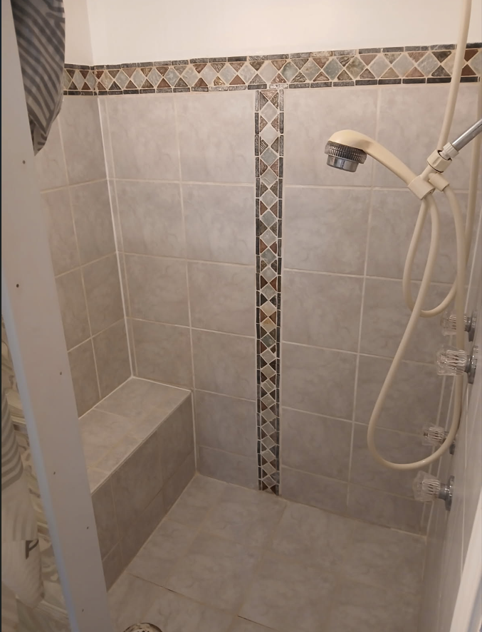 Bathroom shower after professional cleaning - sparkling clean tiles with pristine grout and polished surfaces