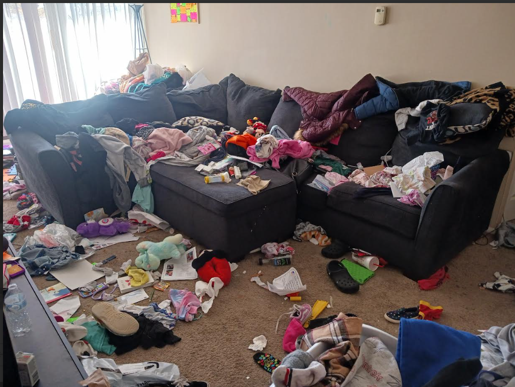 Living room before cleaning - messy with clothes and items scattered